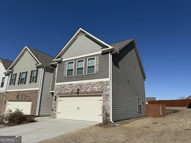 craftsman-style house with a garage, stone siding, fence, and driveway