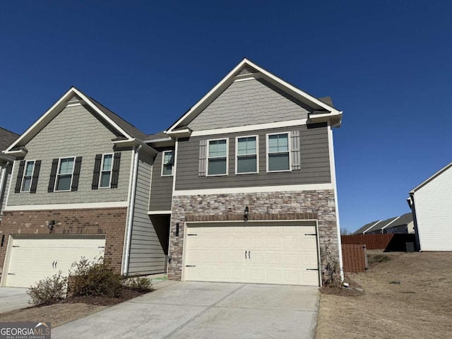 craftsman-style house with concrete driveway, stone siding, an attached garage, and brick siding