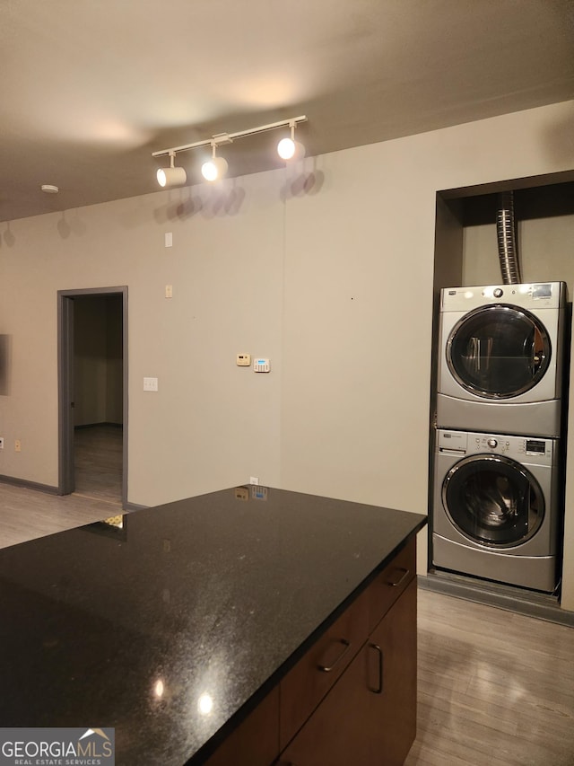 laundry area featuring laundry area, light wood-style flooring, and stacked washer and clothes dryer