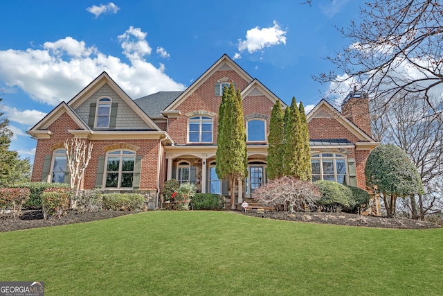 view of front of property with brick siding, a front lawn, and a chimney