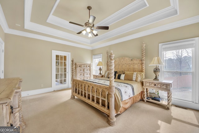 bedroom with light carpet, visible vents, a tray ceiling, and baseboards