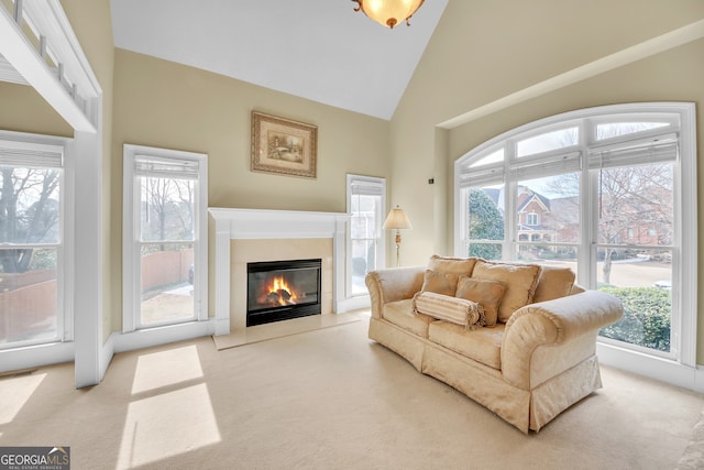 living area with light carpet, plenty of natural light, a fireplace with flush hearth, and high vaulted ceiling