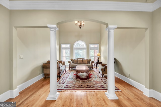 living area featuring ornate columns, baseboards, arched walkways, and wood finished floors