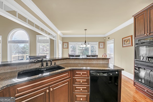 kitchen featuring light wood finished floors, dark stone counters, crown molding, black appliances, and a sink