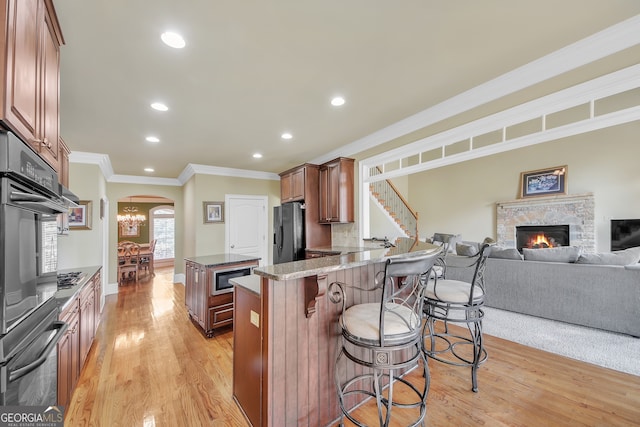 kitchen with arched walkways, a breakfast bar area, stainless steel appliances, open floor plan, and light wood-type flooring