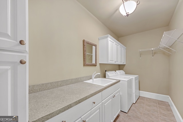 laundry area featuring light tile patterned floors, separate washer and dryer, a sink, baseboards, and cabinet space