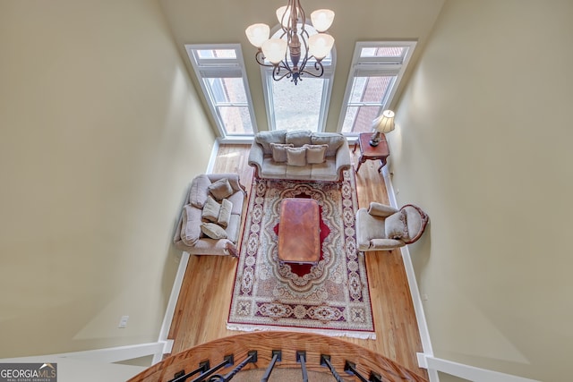 living room featuring a notable chandelier, baseboards, and wood finished floors