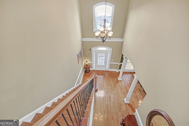 entryway with a high ceiling, baseboards, stairs, light wood finished floors, and an inviting chandelier