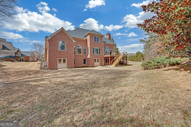 back of house with brick siding, stairway, a lawn, a wooden deck, and a chimney