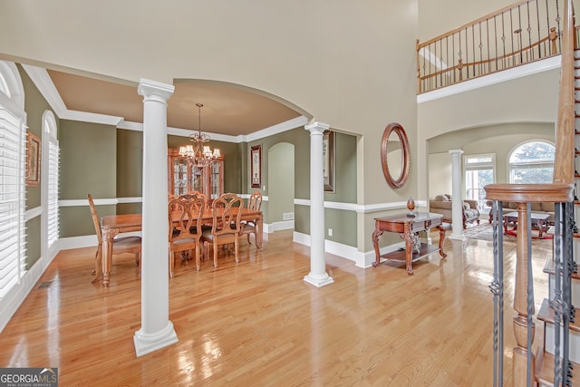 dining area featuring arched walkways, light wood-type flooring, decorative columns, and baseboards