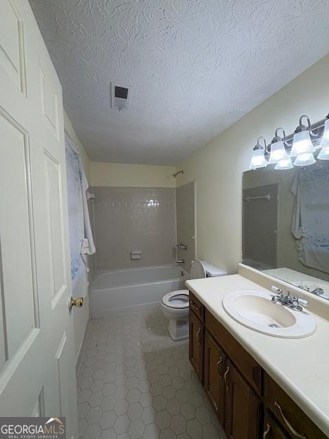 full bathroom featuring toilet, tub / shower combination, a textured ceiling, and vanity