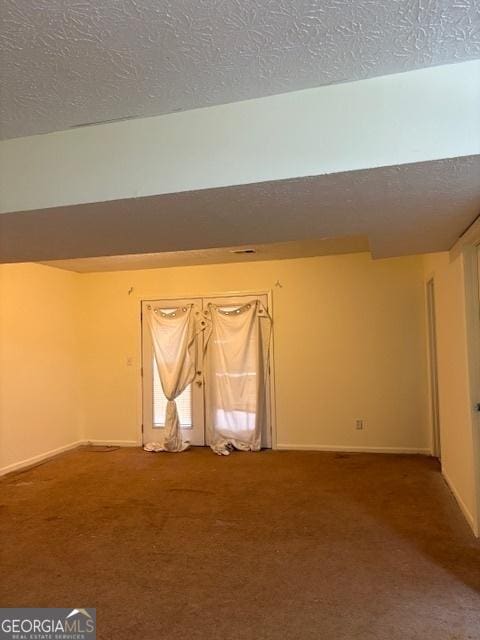 empty room featuring a textured ceiling, carpet flooring, and baseboards