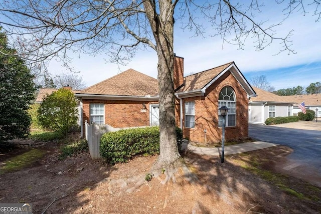 single story home with brick siding, a chimney, and roof with shingles