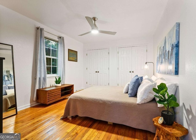 bedroom featuring hardwood / wood-style flooring, ceiling fan, baseboards, and multiple closets