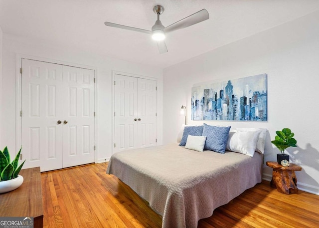 bedroom featuring ceiling fan, wood finished floors, and two closets