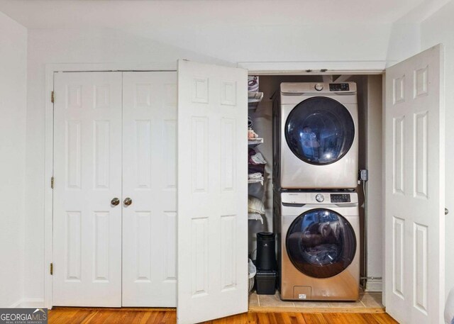 washroom with stacked washer / drying machine, laundry area, and wood finished floors