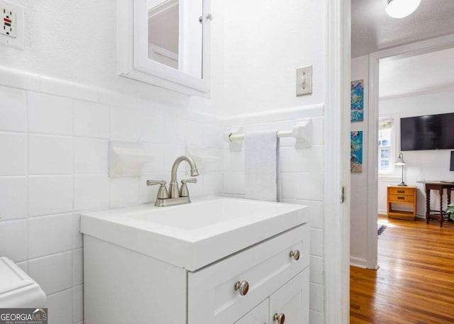 bathroom featuring wood finished floors, vanity, and tile walls