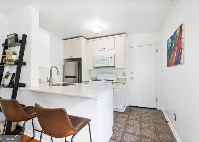 kitchen with range, white microwave, a peninsula, light countertops, and a sink