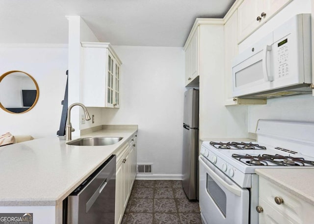 kitchen with a sink, visible vents, light countertops, appliances with stainless steel finishes, and glass insert cabinets