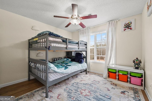 bedroom featuring a textured ceiling, baseboards, and wood finished floors