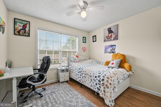 bedroom with a textured ceiling, ceiling fan, dark wood-type flooring, and baseboards