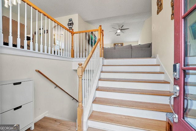 stairs featuring wood finished floors and a ceiling fan