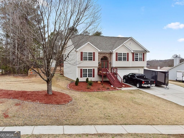 split foyer home with brick siding, roof with shingles, concrete driveway, an attached garage, and a front lawn