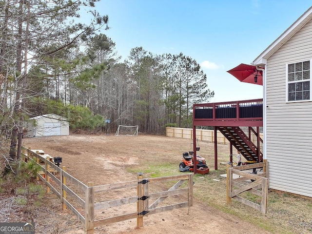 view of yard featuring a storage shed, a gate, a deck, an outdoor structure, and stairs