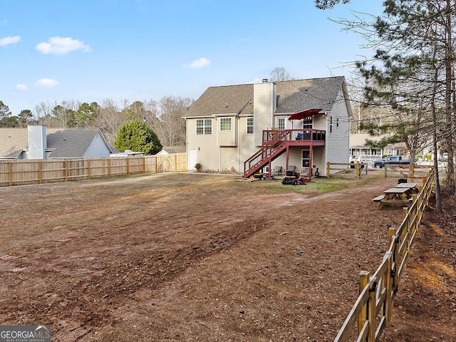 rear view of property featuring a deck, a chimney, a fenced backyard, and stairway