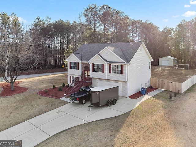 raised ranch featuring a shingled roof, a front yard, driveway, and fence