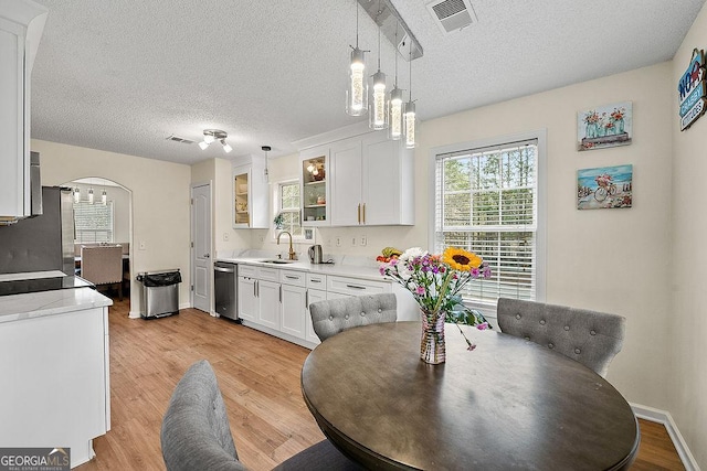 dining room with arched walkways, visible vents, a textured ceiling, light wood-type flooring, and baseboards