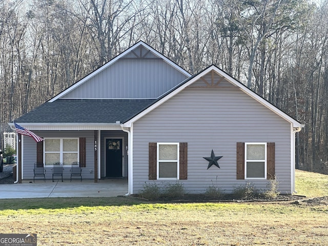 view of front of house with a front lawn and a shingled roof