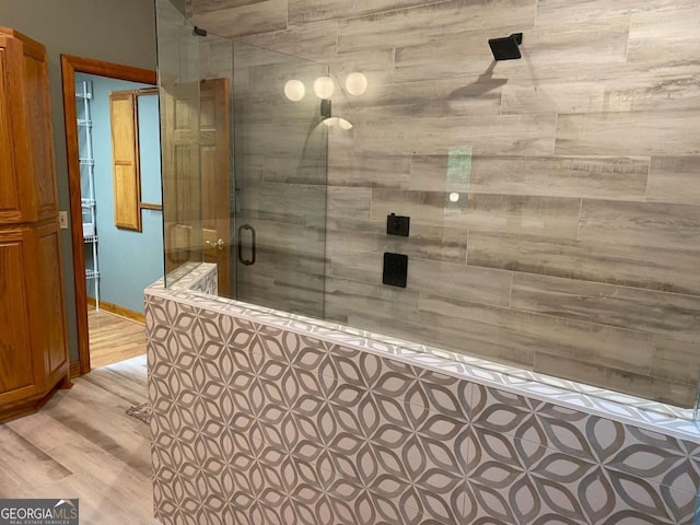 full bath featuring wood finished floors and a tile shower