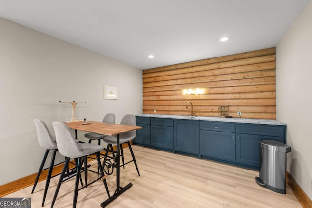 interior space featuring indoor wet bar, log walls, light wood finished floors, recessed lighting, and baseboards