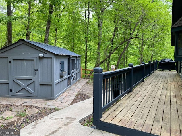 deck with a grill, a storage unit, and an outdoor structure