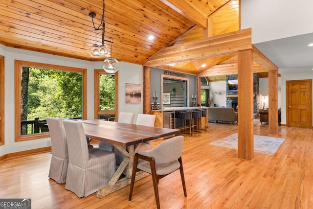 dining area featuring baseboards, lofted ceiling, wood ceiling, a stone fireplace, and light wood-style floors