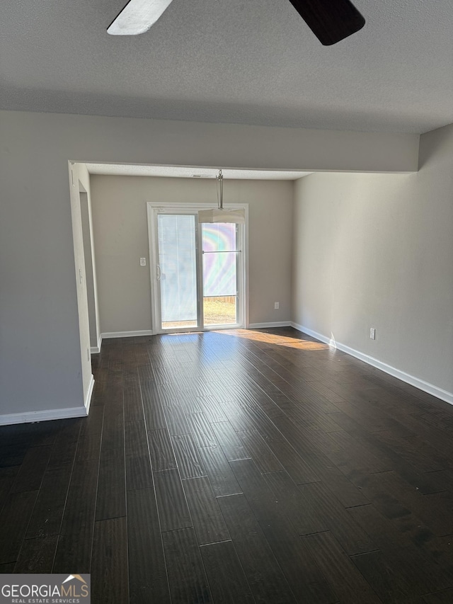 empty room with ceiling fan, a textured ceiling, baseboards, and dark wood-style flooring