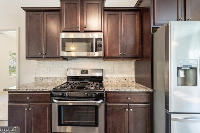 kitchen featuring tasteful backsplash, appliances with stainless steel finishes, dark brown cabinets, and light stone counters