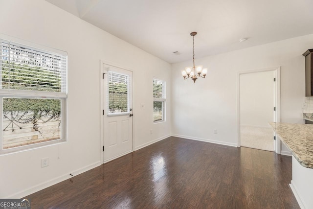 unfurnished dining area featuring baseboards, dark wood-style flooring, visible vents, and a notable chandelier