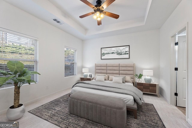 bedroom with ceiling fan, baseboards, visible vents, and a raised ceiling