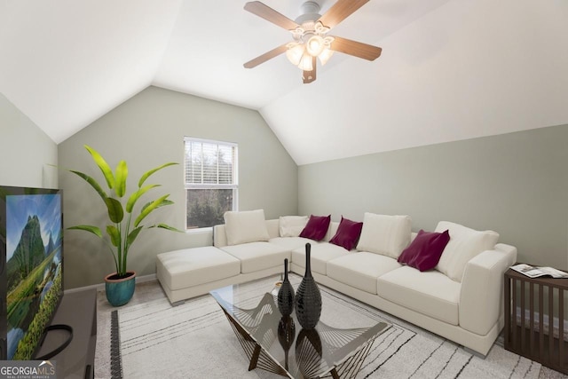 living room with a ceiling fan, light colored carpet, vaulted ceiling, and baseboards