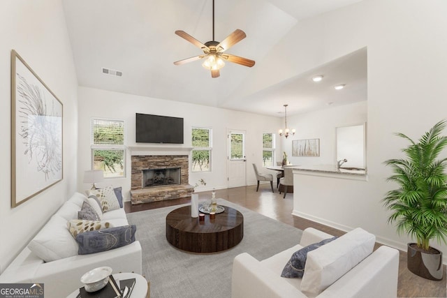 living area featuring lofted ceiling, visible vents, dark wood-type flooring, and ceiling fan with notable chandelier