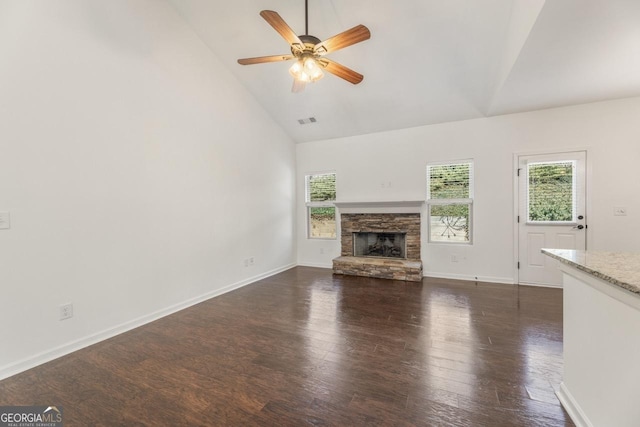 unfurnished living room featuring visible vents, dark wood-type flooring, a ceiling fan, a stone fireplace, and baseboards