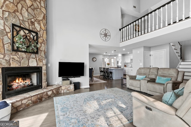 living area featuring a fireplace, wood finished floors, visible vents, baseboards, and stairway