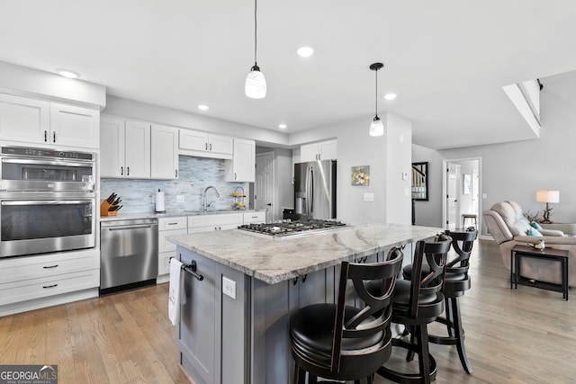 kitchen with pendant lighting, appliances with stainless steel finishes, a kitchen bar, and white cabinets