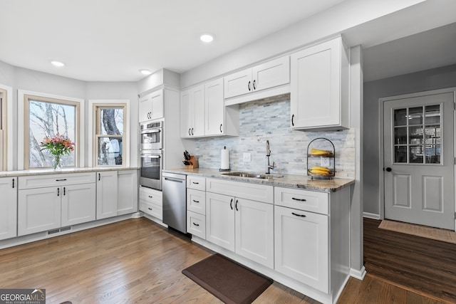 kitchen with light stone counters, white cabinets, and a sink