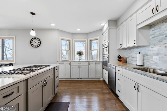 kitchen with light stone counters, stainless steel appliances, white cabinetry, and hanging light fixtures