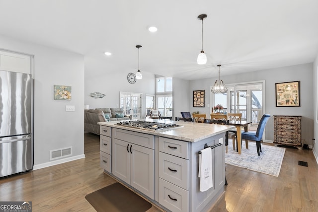 kitchen with visible vents, a kitchen island, open floor plan, stainless steel appliances, and pendant lighting