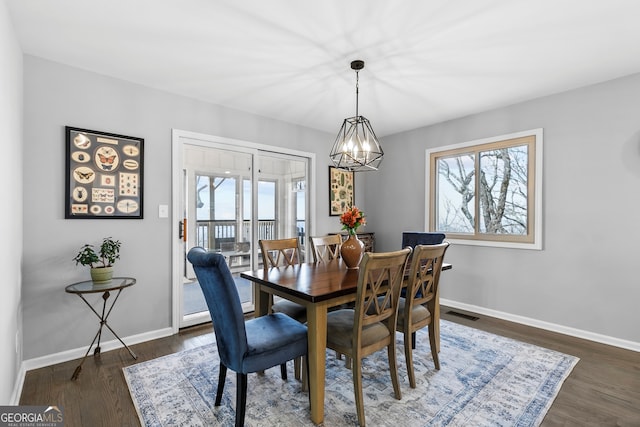 dining room with a chandelier, plenty of natural light, dark wood finished floors, and baseboards