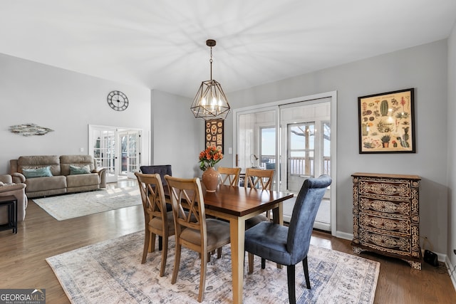 dining area featuring a chandelier, french doors, dark wood-style flooring, and baseboards